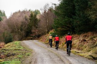 Three male cyclists riding uphill on gravel