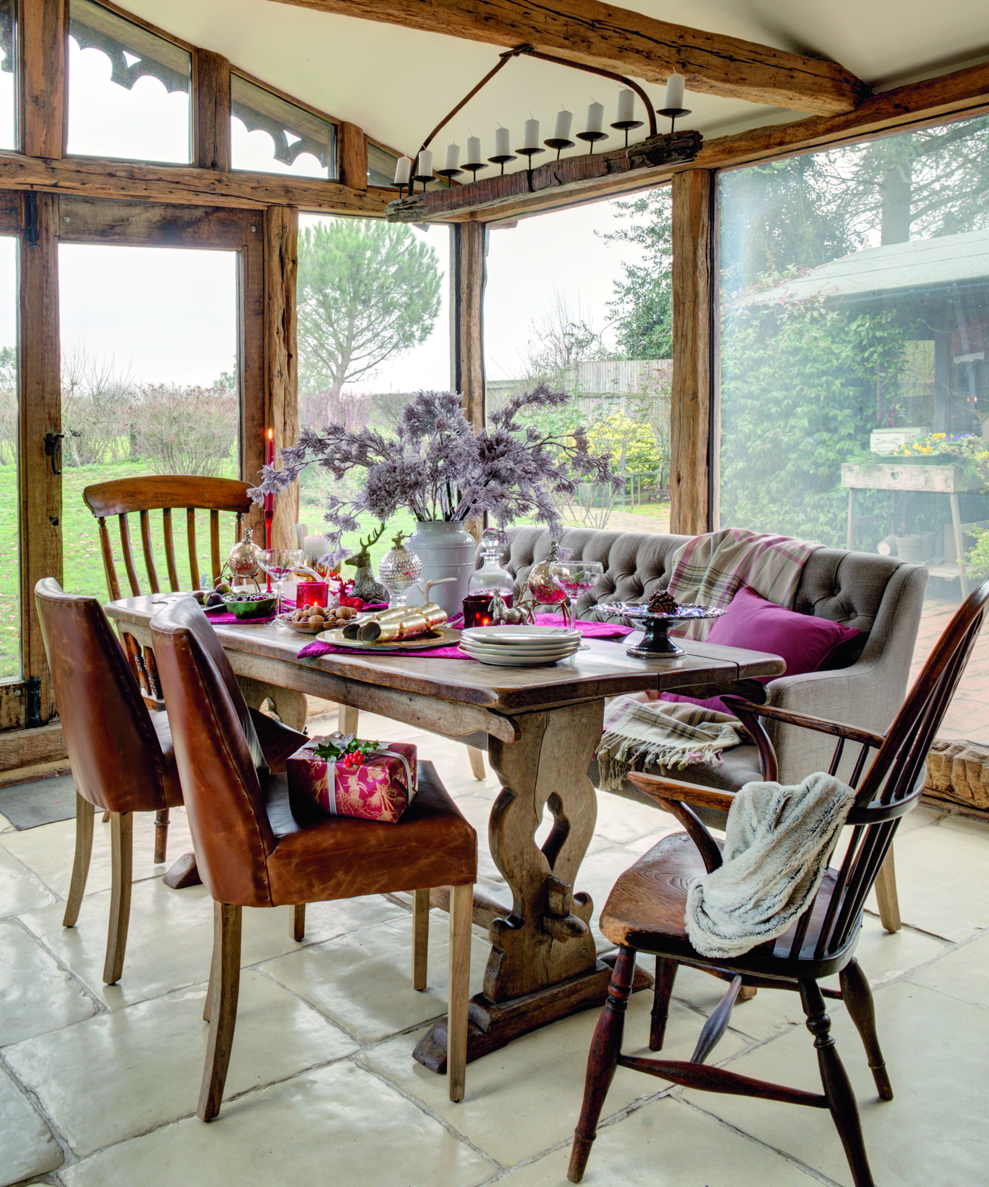 Wood beamed orangery idea with mismatched dining tables