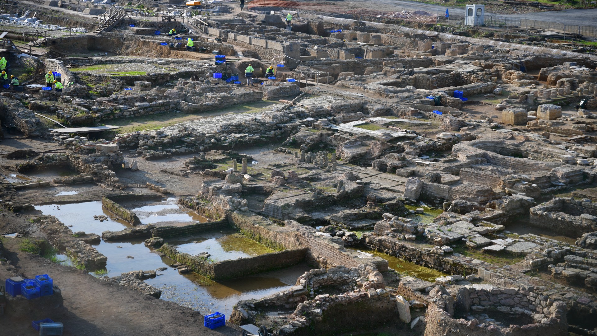 Panoramic view of the excavation site in Istanbul, Turkey. There are quite a few foundations made of stone bricks. There was a team of high-visibility helmeted men exploring the ruins.