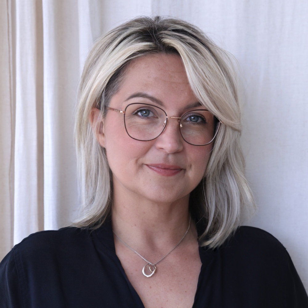 female with blond hair, glasses wearing black top