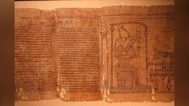 This image shows a part of the Book of the Dead. On the left is a block of hieratic text. On the right is an image appears to show Osiris, the ancient Egyptian god of the underworld.