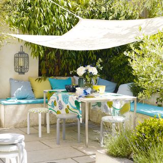 Blue and white outdoor sofa with shade sail covering it