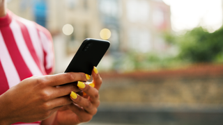 Close up for woman with yellow painted fingernails using smart phone