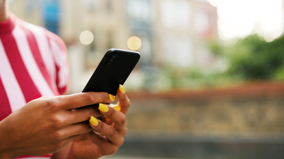 Close up for woman with yellow painted fingernails using smart phone