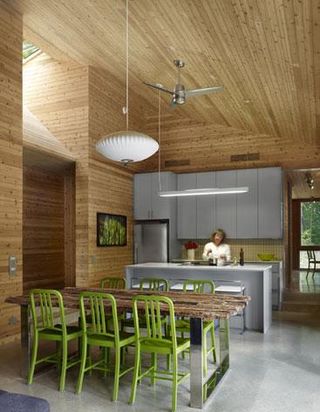 Open plan kitchen with a wooden bench and green chairs