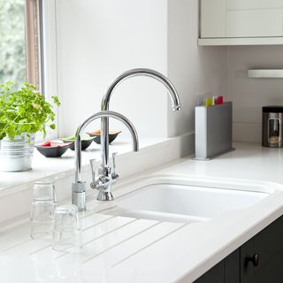 kitchen with white wall and sink with water glasses on worktop