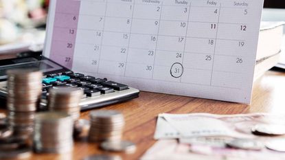 stacks of coins and calculator by calendar