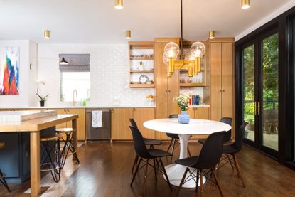 oval dining table shape in white kitchen with wood cabinets by Maestri Studio