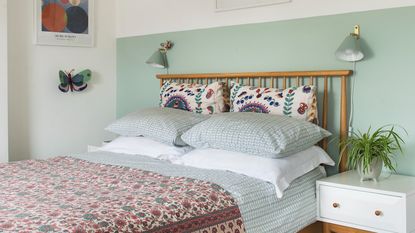 A bed with a fabric-covered headboard and lots of pillows and cushions atop