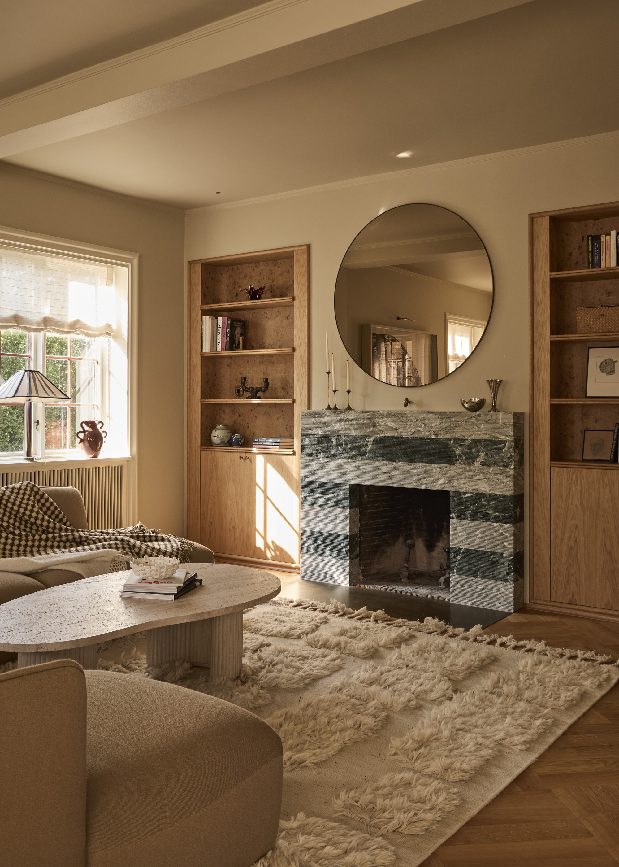 A living room with Scandi style influence, including a fluffy rug, a striped stone fireplace, and alcove bookshelves