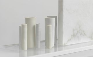A closer look at the cylindrical-shaped ceramic vessels in light gray and light yellow.