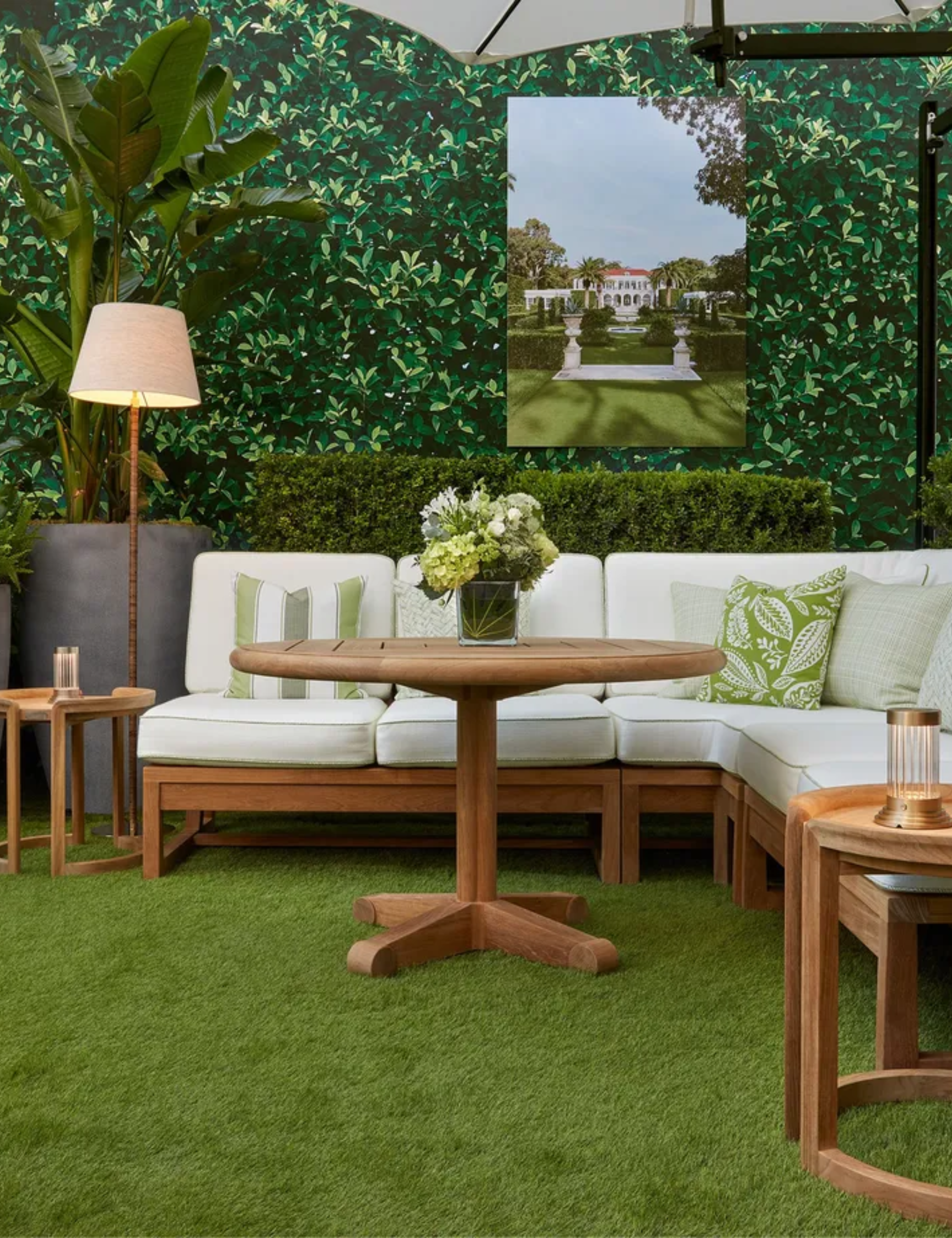 Faux grass-floored terrace with crawling vines, patterned throw pillows, and wooden patio furniture