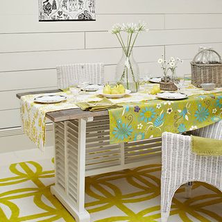dining room with white wall and dining table with yellow printed table cloth