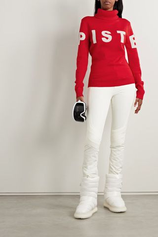 cold weather clothing - woman wearing red turtleneck jumper reading 'piste'