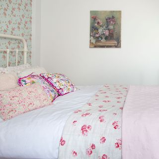 bedroom with pink floral printed wall and white bed with printed pillows