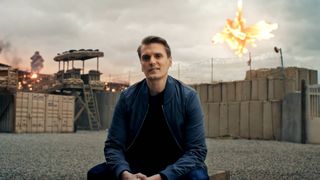 DICE senior producer David Sirland talks to the camera while a helicopter explodes in midair behind him in the Battlefield 6 multiplayer reveal showcase.