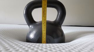 Nectar mattress review, with a 50lb kettlebell in the middle of the bed to measure pressure relief