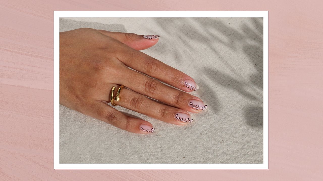 A close up of hand, wearing rings, with subtle leopard print nails - resting on a cream backdrop, with plant shadows/ in a pink, textured template