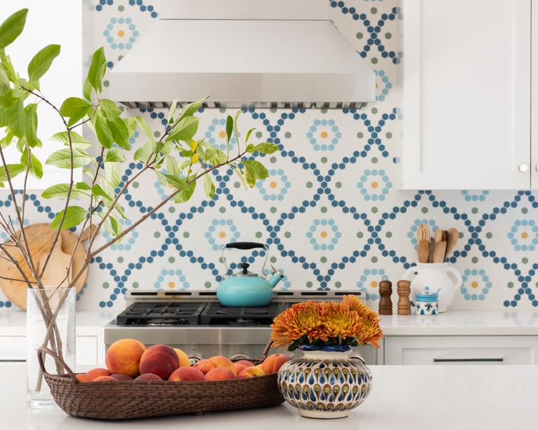 A white kitchen with blue island, and white and blue patterned tile backsplash ideas. 