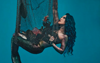 A picture of Alissa White-Gluz dressed as a mermaid in a fishing net for a PETA campaign