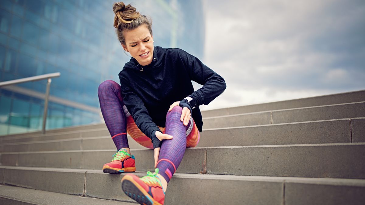 Injured runner sitting on steps holding calf