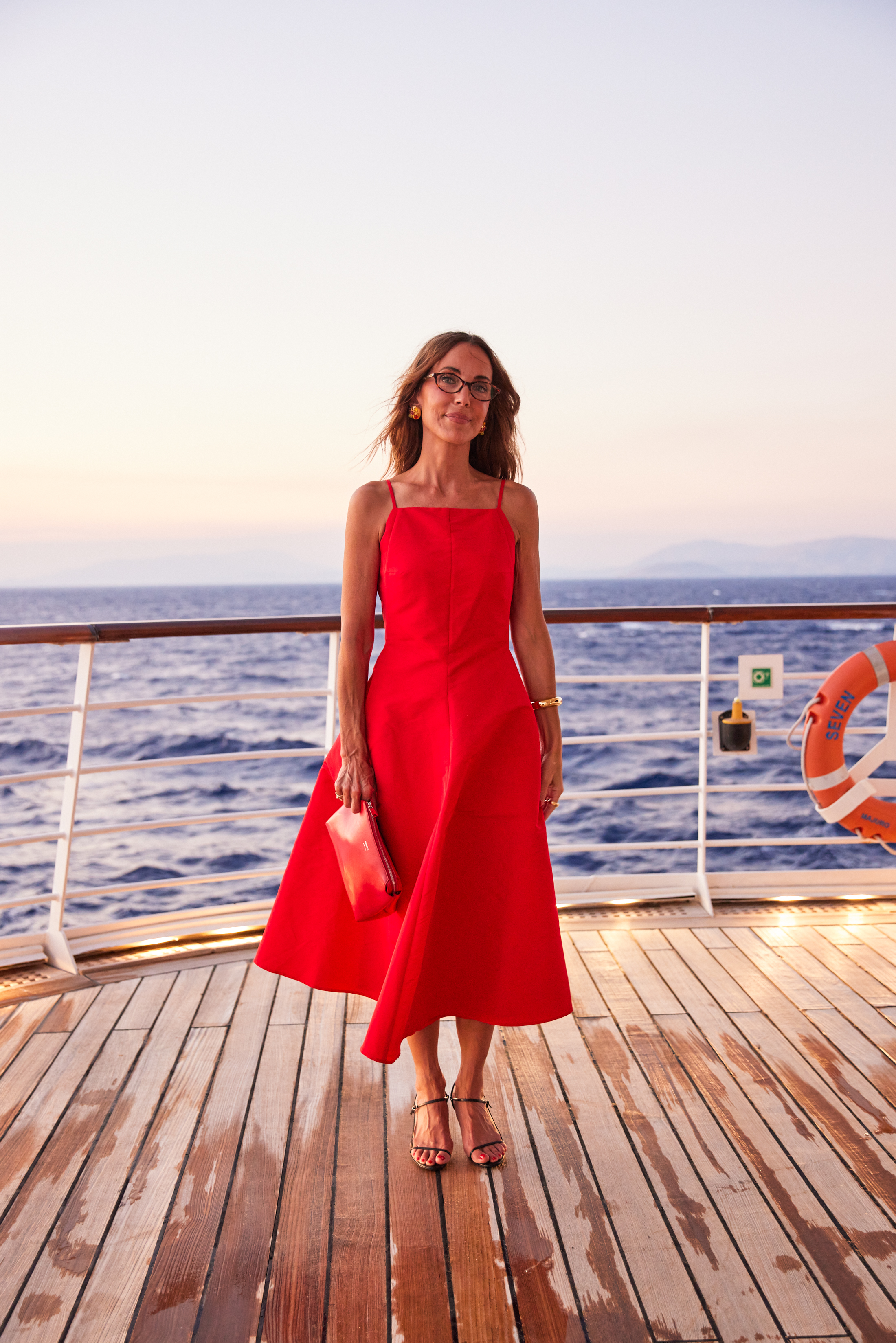 Larissa Mills wears a waisted red dress on a boat