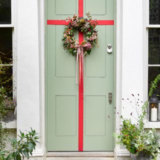 Entrance door decorated with a red ribbon and a wreath