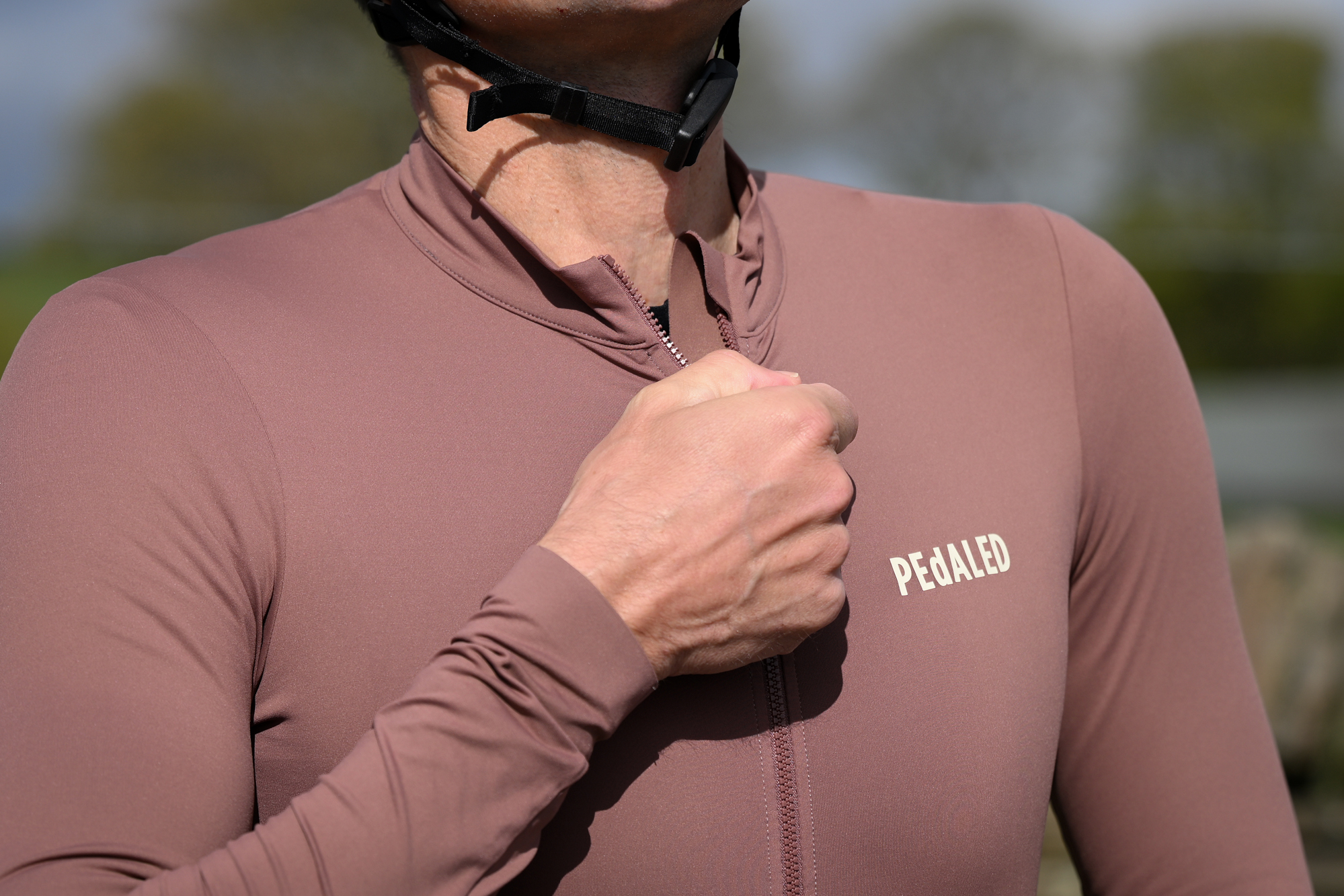 close up of a man wearing a purple long sleeved jersey doing up the zip