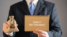 An executive holds a bag of money and a notebook that says "early retirement."