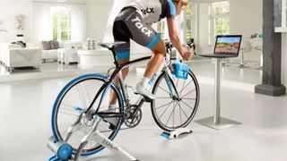 Tacx Vortex Smart Bike Trainer review: an image showing a woman cycling in her living room using the Tacx indoor bike trainer