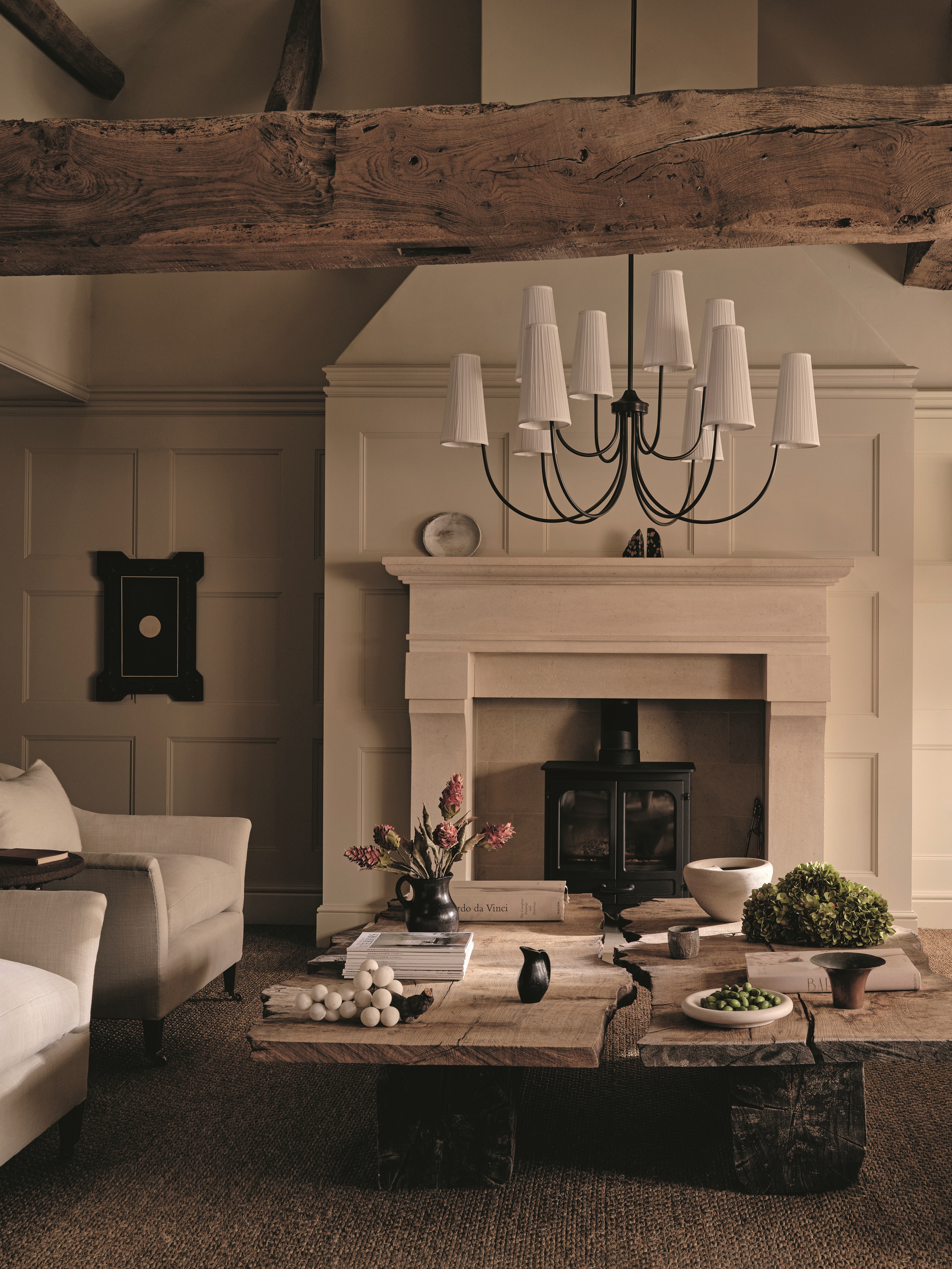 a living room with traditional paneling, a large fireplace, and dramatic chandelier