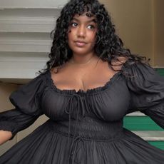 Woman wears black shirred dress by Doen