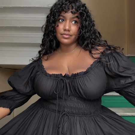 Woman wears black shirred dress by Doen