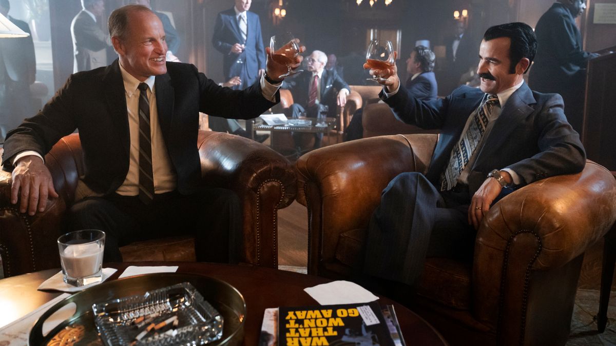 Woody Harrelson and Justin Theroux toasting drinks in a lounge in White House Plumbers.