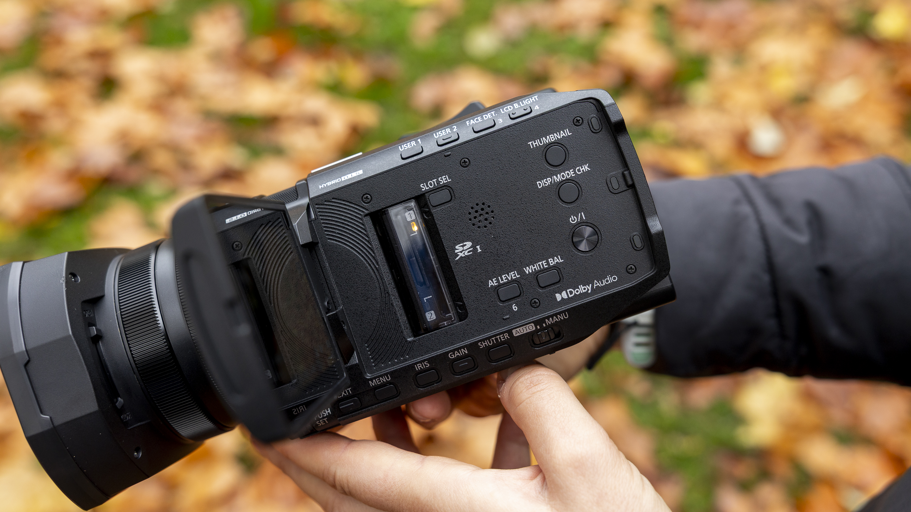 The Panasonic HC-X1200 camcorder held by a female photographer against an orange autumnal backdrop
