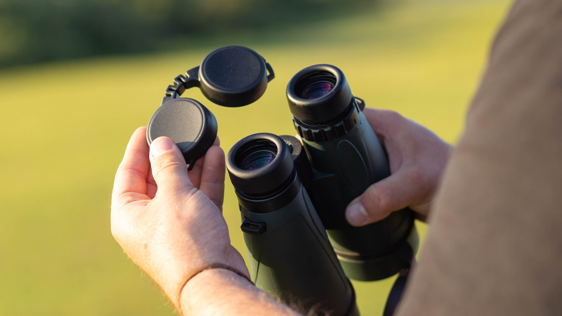 The lens caps of the Celestron Nature DX 12x56 binoculars being hand held