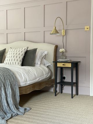 Bedroom with bed and nightstand, wall lamp, wood paneling, and sisal flooring