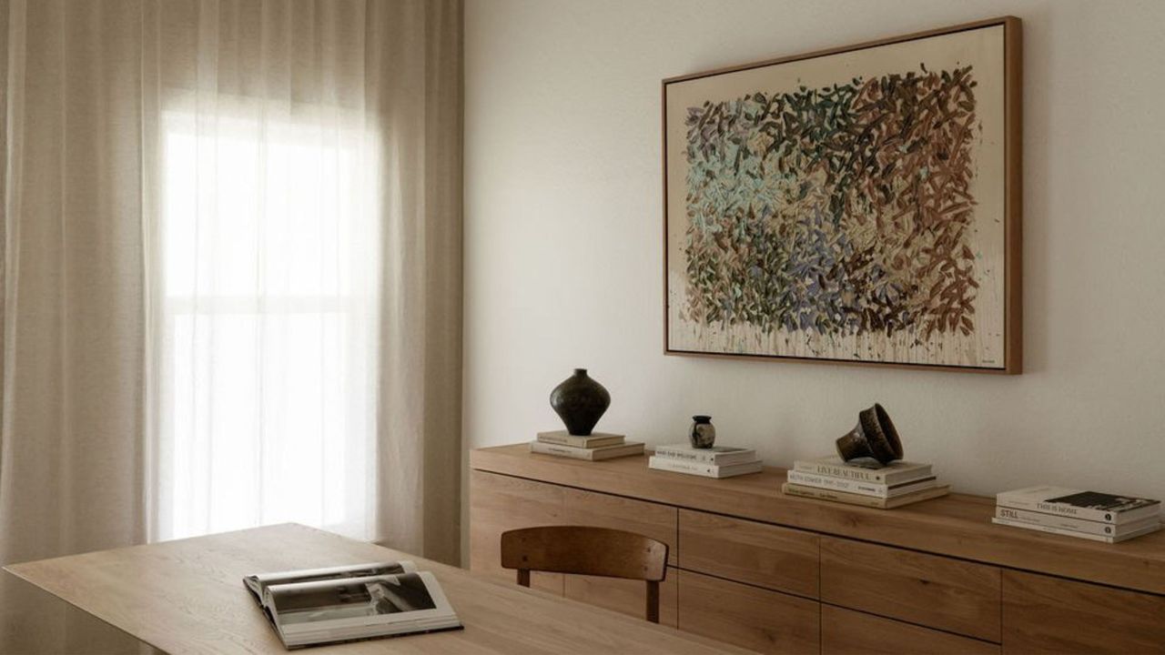 minimalist home office with console styling and artwork. Wooden textures have been used across different areas of the room 