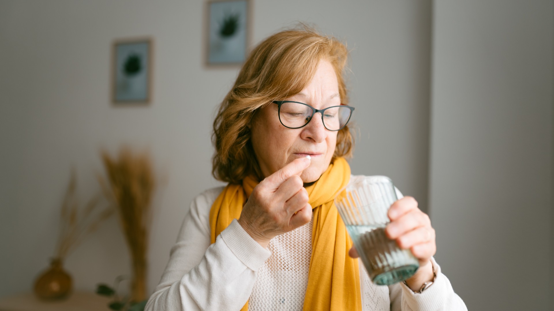 Older woman taking a pill with a glass of water
