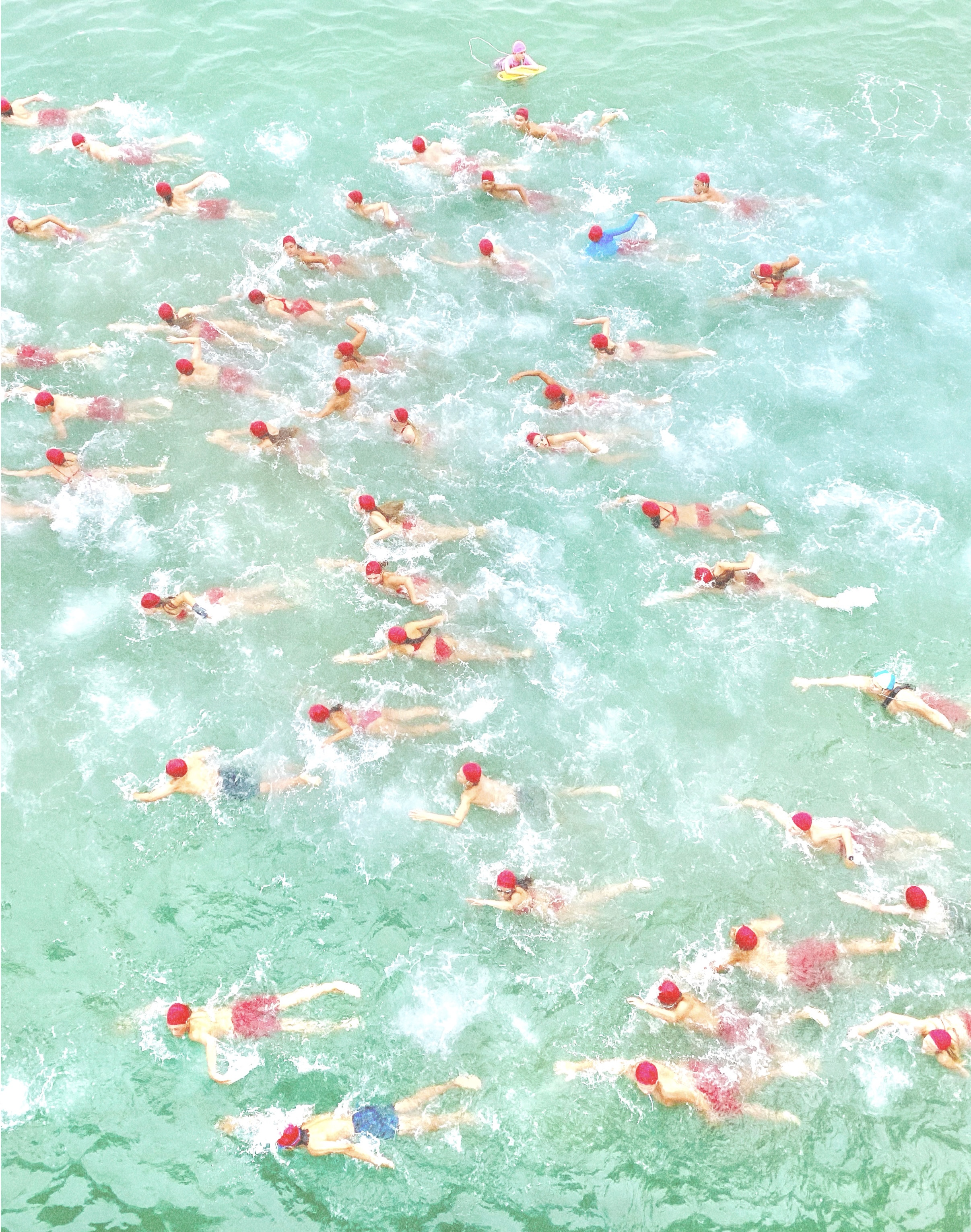 A group of swimmers in red caps in a green river