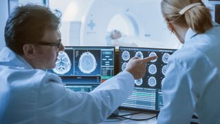 Two clinicians analyse a brain readout from an MRI scan