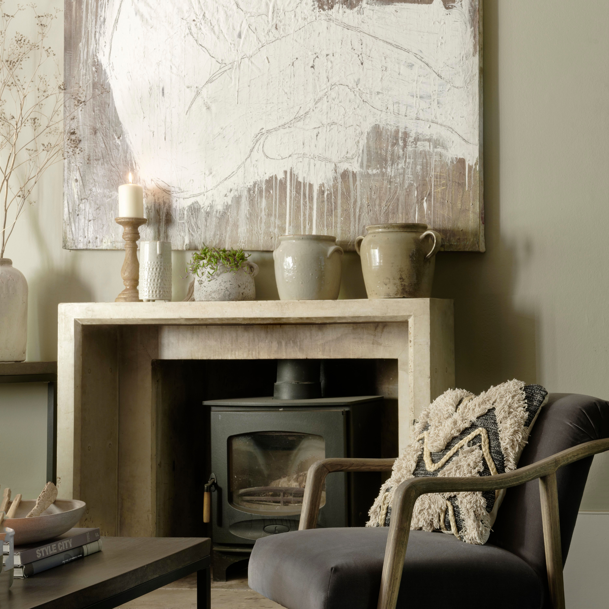 Neurtral fireplacewith vases, candlestick hold and texture art piece hanging above.