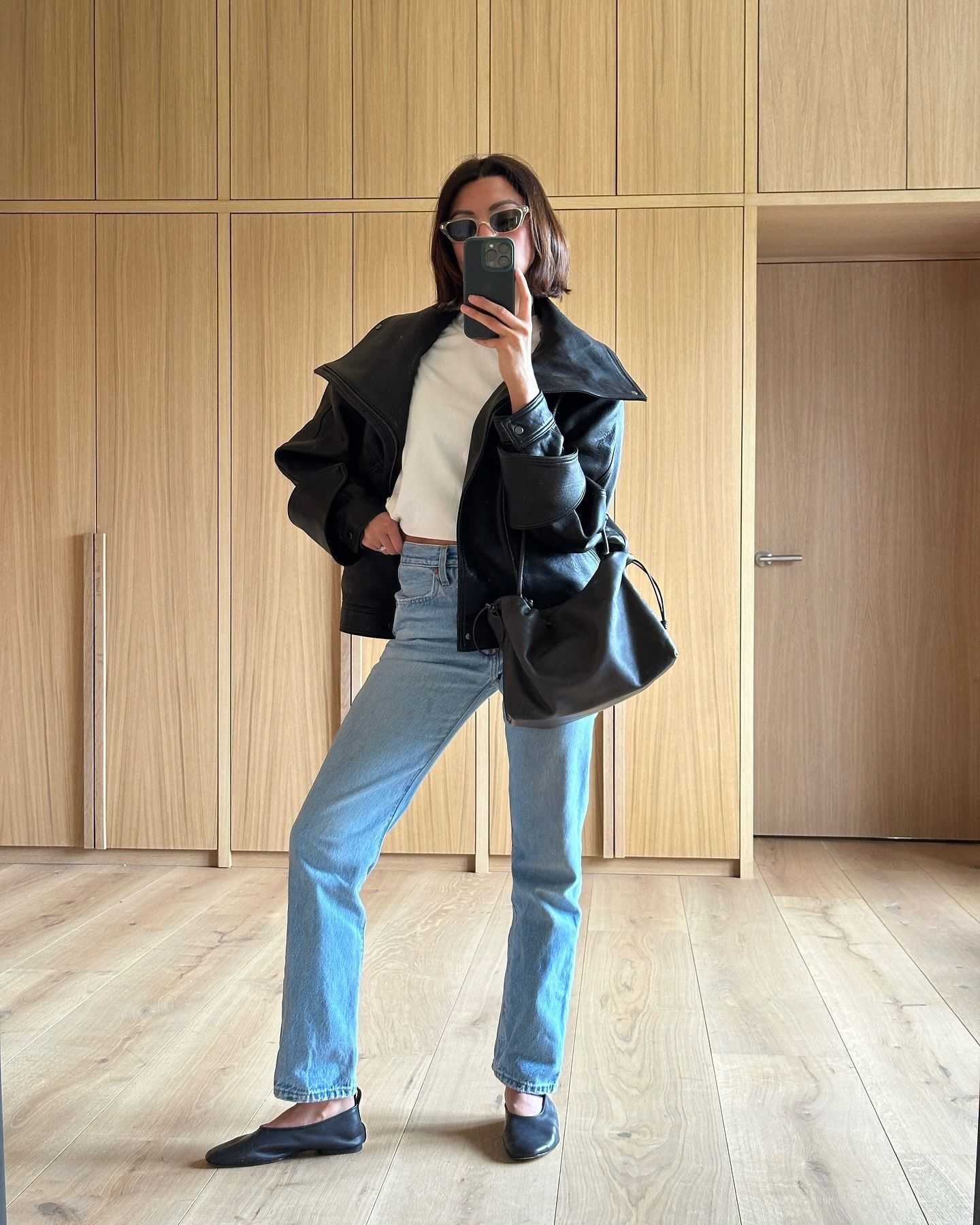 @smythsisters wearing a white T-shirt and jeans outfit with a black leather jacket, glove flats, and a leather bag