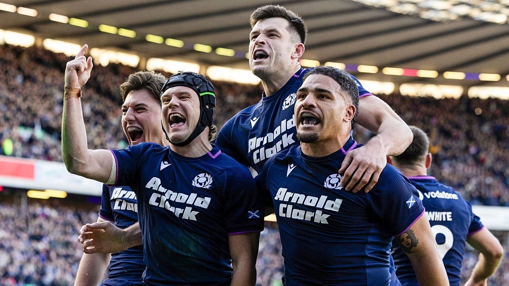 Darcy Graham, wearing a scrum cap, is surrounded by his Scotland teammates after scoring a try against France in the Six Nations 2026.
