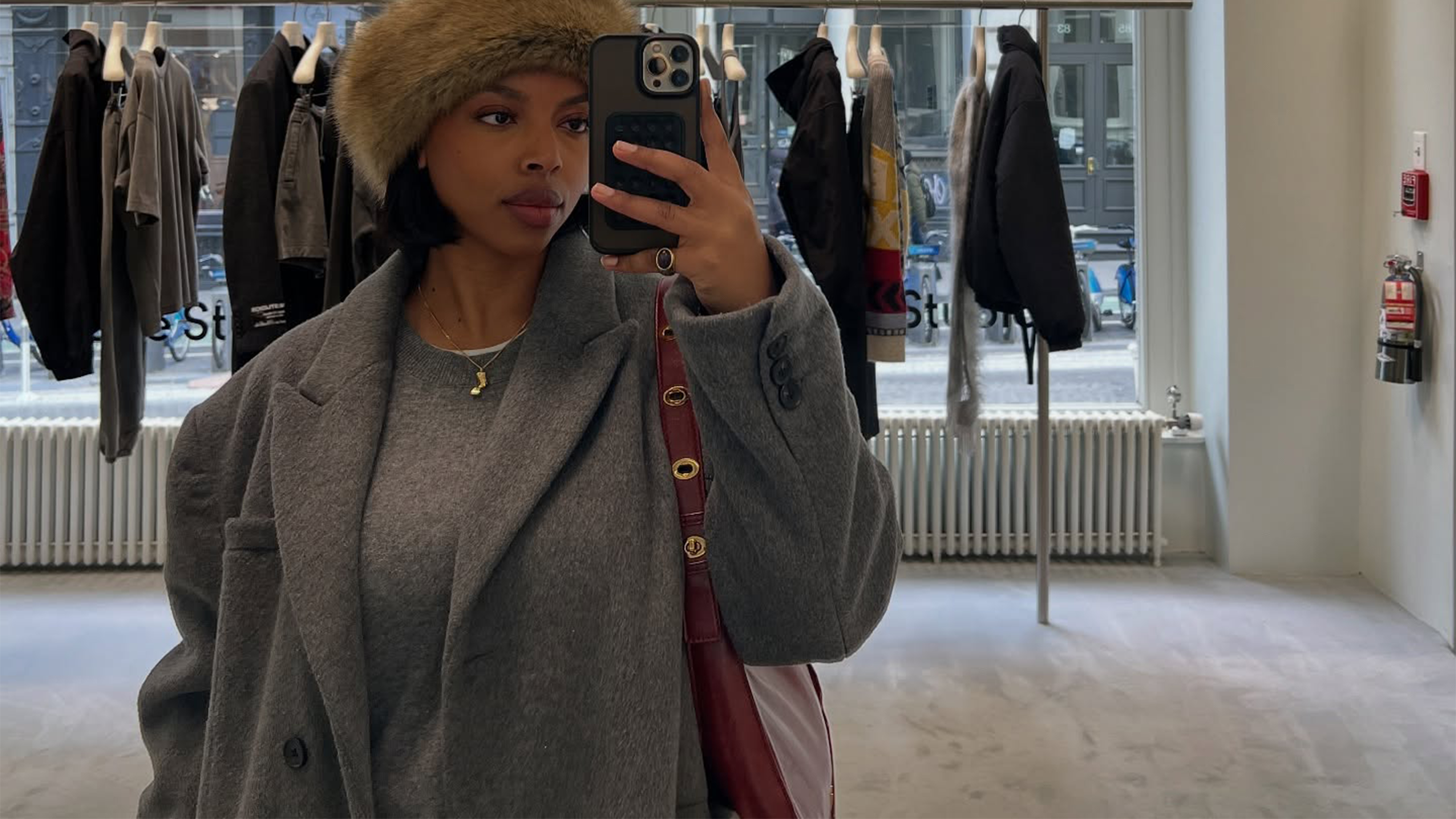 @aysha.sow in a grey crewneck sweater and a blazer coat wearing the faux-fur hat trend