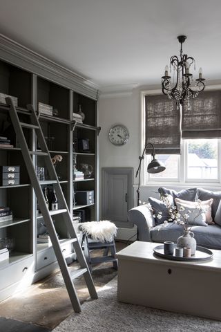 living room space with flagstone floors gray sofa and gray open shelves with ladder
