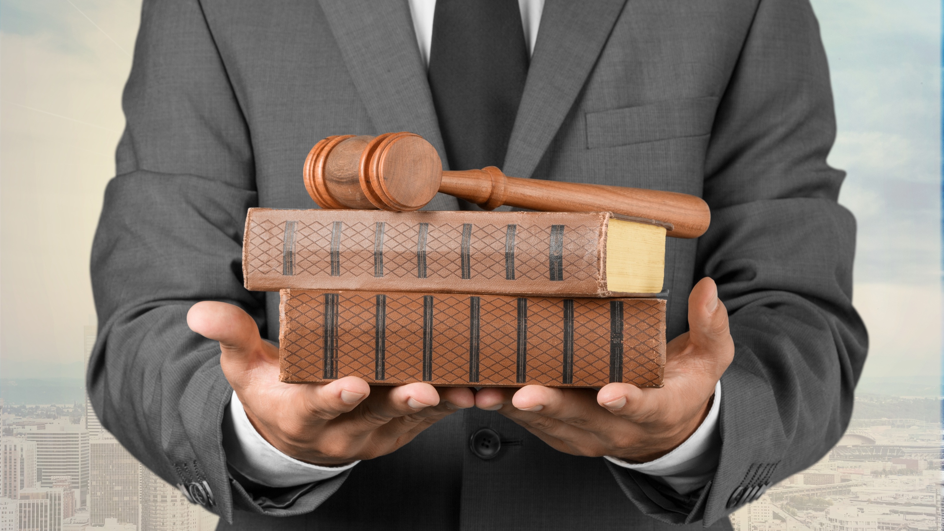 A man in a business suit holds law books and a judge's gavel.