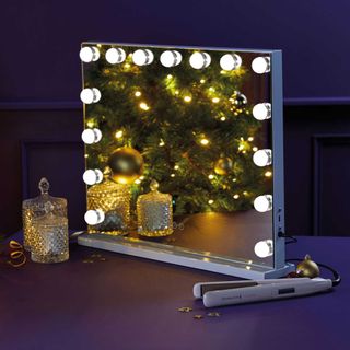 Aldi Hollywood mirror with lights on table next to decorative glass jars and hair straightener