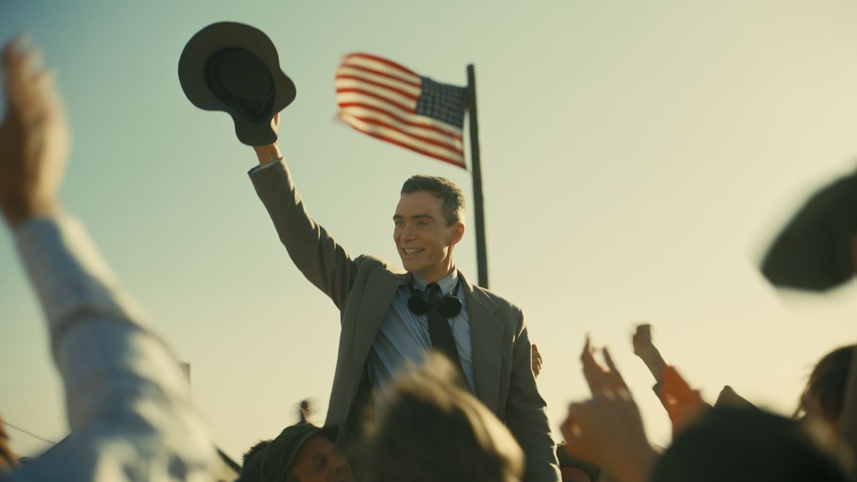 Cillian Murphy&#039;s Robert J Oppenheimer holds his hat and smiles at an assembled crowd in Christopher Nolan&#039;s Oppenheimer movie