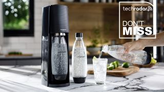 A black SodaStream Terra sparkling water maker with bottles on a countertop and a TechRadar deals badge overlay